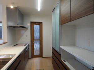 川越市新築戸建住宅システムキッチンとカップボード画像です。木目調のシステムキッチンパネルとカップボードが写っています。