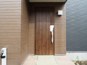 ふじみ野市内新築工事の玄関ポーチ、濃いめのブラウン木目調のドアが落ち着いた雰囲気です