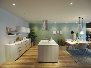 TOTO川越ショールームに展示されている、キッチン。白いアイランドキッチンとダイニングテーブルの上に食器などが並んでいます