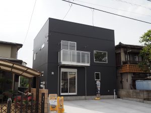 狭山市内に新築した箱型デザインの戸建住宅は濃いグレーガルバリウムを使用した外壁です。スタイリッシュな窓が写っています。