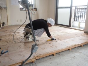 プレミール和光リフォームの施工中、リビングルームで職人が床を剝がし下地調整をしています