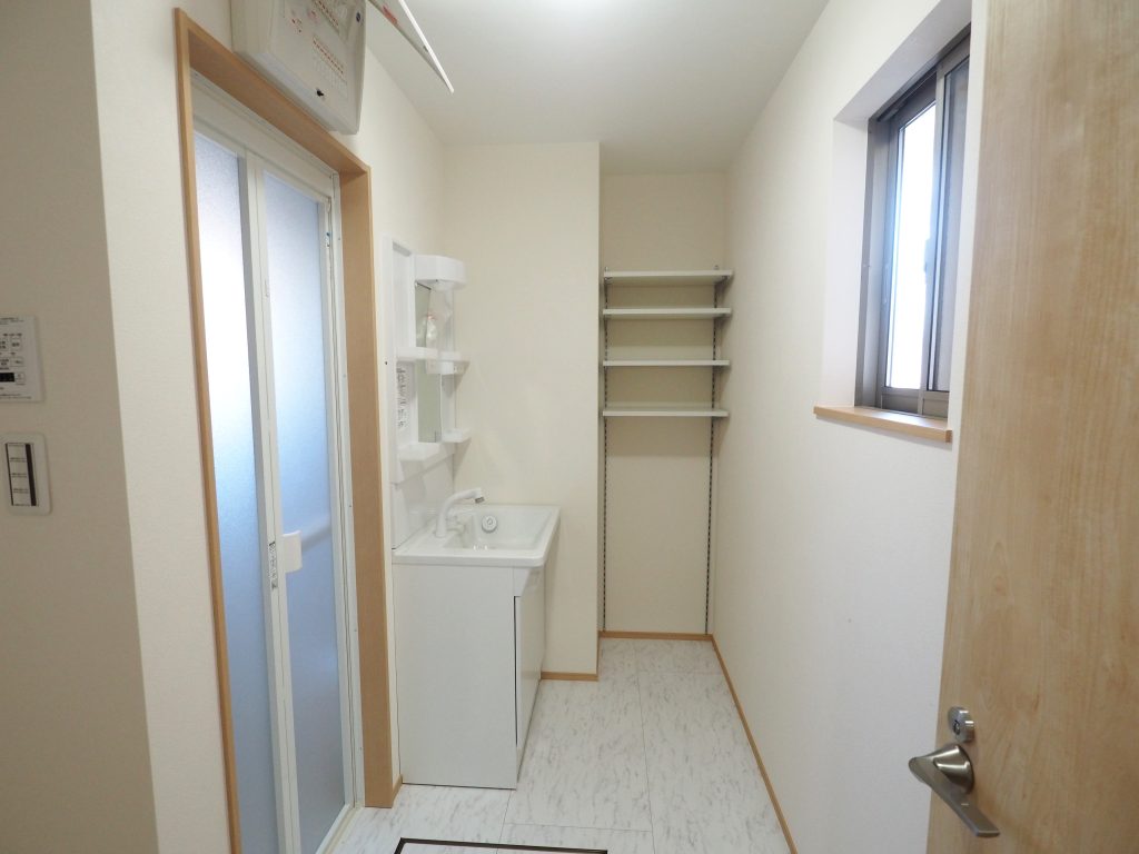 所沢市内戸建て住宅の洗面時すぺーすです。白い洗面化粧台と可動棚が写っています。