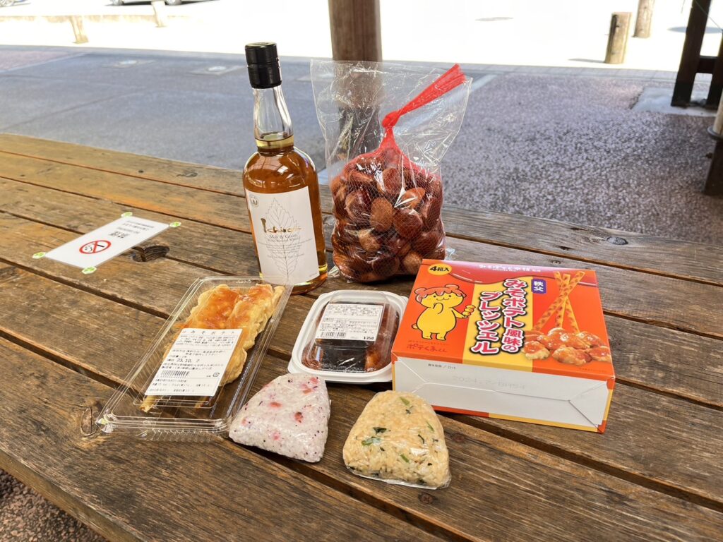 道の駅あしがくぼで買ったウィスキー、栗、味噌ポテト、あげ餅、おにぎり2個、味噌ポテトのお菓子が写っています。